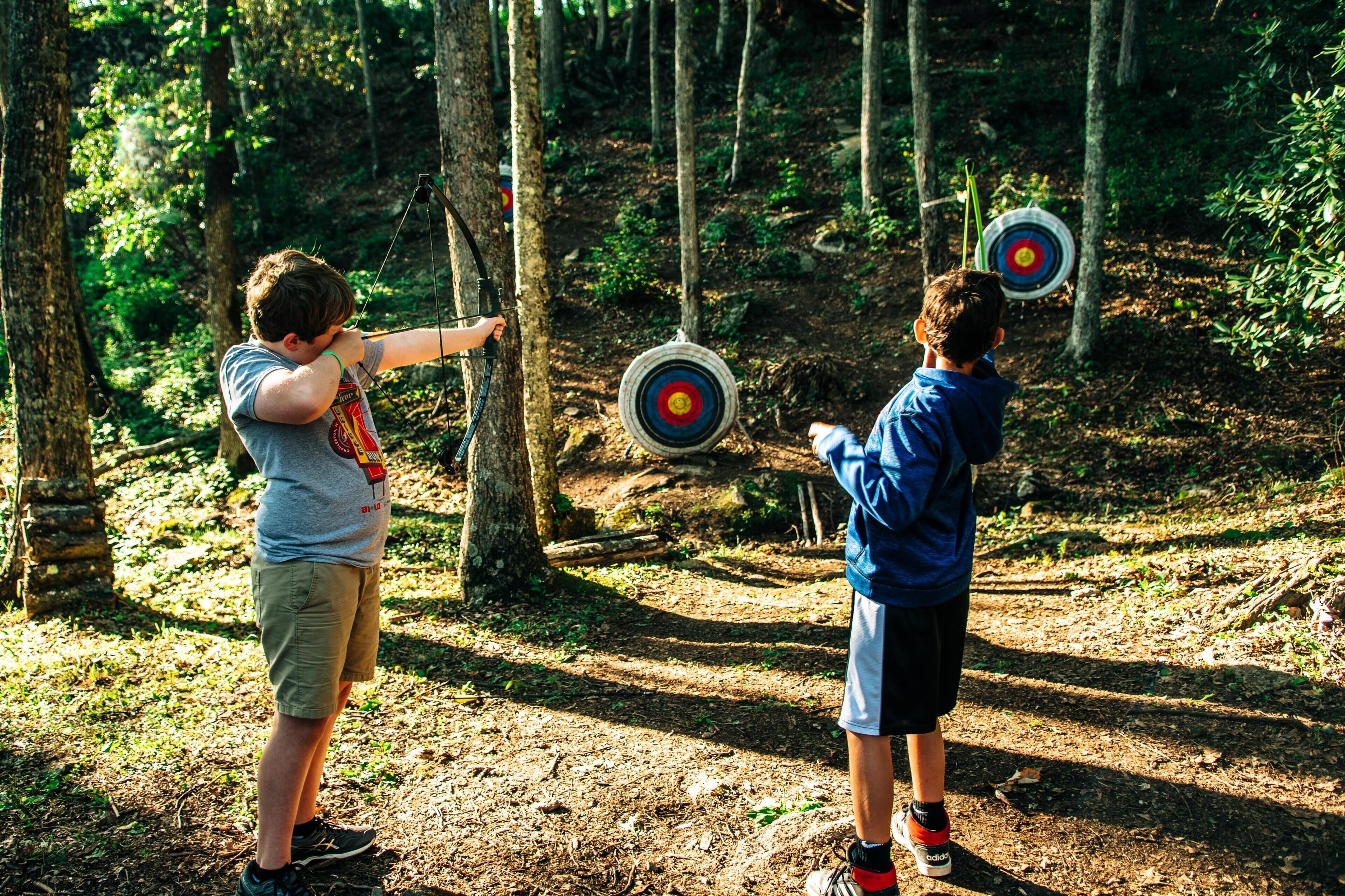 Two individuals aiming at targets in a forested area.