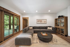 Ein modernes Wohnzimmer mit Ecksofa, rundem Couchtisch und Bücherregal.
