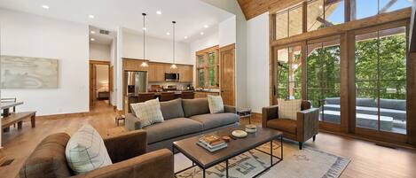 A spacious living area with a large sofa, coffee table, and a view of the outdoors through large windows.