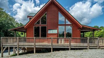 A wooden cabin with a triangular roof, large windows, and a wooden deck.