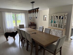 Ein Essbereich mit Holztisch, Stühlen, einem Schrank und einem Hund.