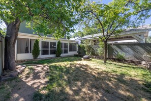 A residential backyard with a covered patio, a tree, and a stone wall. - Spacious 4-bedroom modern cottage in beautiful Prescott with AC and large yard (Prescott)