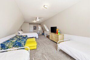 Ein Schlafzimmer mit zwei Betten, einem Deckenventilator, einem Fernseher und einer Kommode.