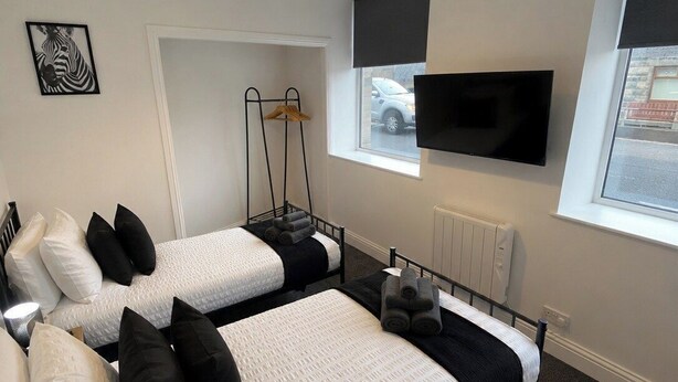 Ett hotellrum med två sängar, en tv, ett element och ett fönster med utsikt.