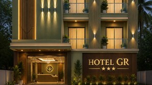 A multi-story hotel with a prominent 'GR' logo, balconies with potted plants, and a well-lit entrance.