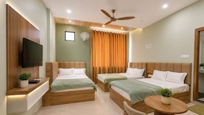 A hotel room with two beds, a TV, a ceiling fan, and a small table with a plant.