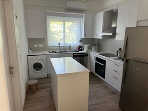 Eine moderne Küche mit einer zentralen Kochinsel, eingebauten Geräten und einem Fenster, das für natürliches Licht sorgt.