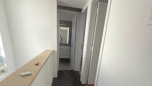 Een smalle gang met een donker tapijt, witte muren en een houten toonbank aan de linkerkant.