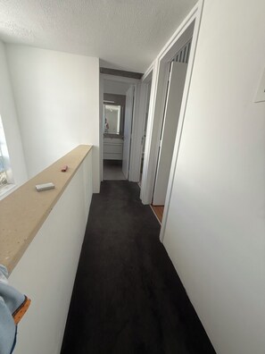 A narrow hallway with a dark carpet, white walls, and a wooden counter on the left. - Protaras Cyprus Beach House (Paralimni)