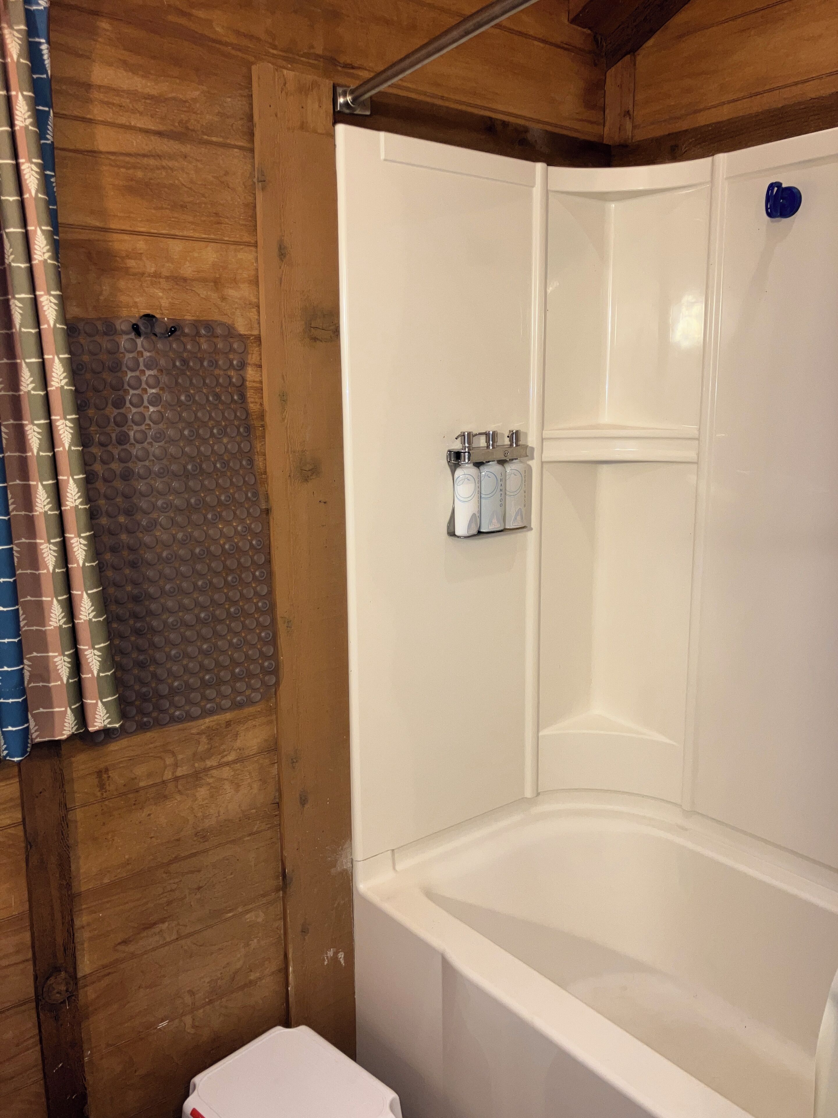 Un espace douche avec une baignoire blanche, un rideau de douche et un ensemble de produits de toilette fixés au mur.
