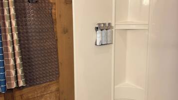 Un espace douche avec une baignoire blanche, un rideau de douche et un ensemble de produits de toilette fixés au mur.