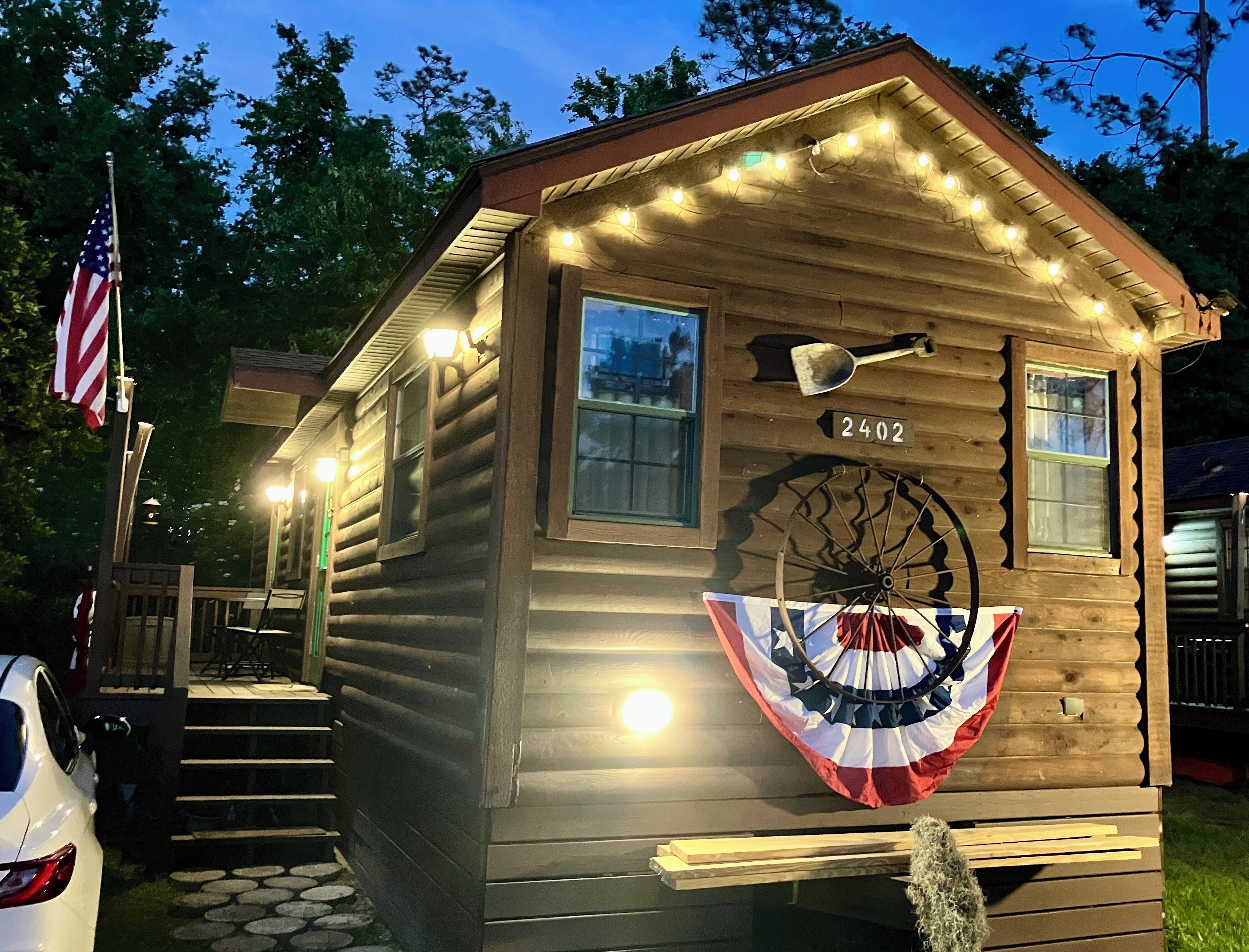Une cabane en bois avec le numéro « 2402 » peint sur le côté, un drapeau et une pelle fixée au mur.