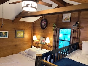 A wooden cabin bedroom with a bed, two wall-mounted lamps, a window with curtains, and a ceiling fan. - Authentic Fort Wilderness family cabin from Walt Disney World, 1/3 Disney prices (Kissimmee)