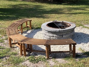 A fire pit with a circular stone design and a wooden bench and table set around it. - Authentic Fort Wilderness family cabin from Walt Disney World, 1/3 Disney prices (Kissimmee)
