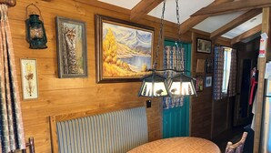 A wooden interior with a round wooden table, bench seating, and a hanging lantern.