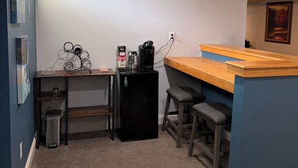 Eine Küchenzeile mit Arbeitsfläche, Hockern, Kühlschrank und Kaffeemaschine.