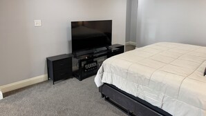 Ein Schlafzimmer mit einem Bett, einem Fernseher auf einem Schrank, einer Kommode und einem Teppichboden.
