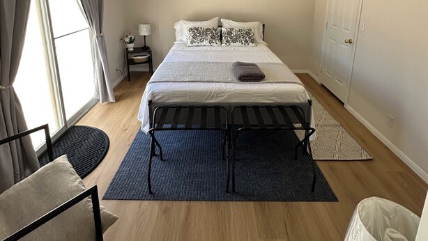 Ein Schlafzimmer mit einem Bett, einem Deckenventilator, einem Nachttisch, einer Lampe und einer Tür.