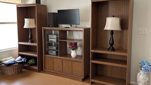 Ein Wohnzimmer mit Holzbögen, einem Flachbildfernseher, einer Lampe, einer Vase mit Blumen und einem Korb.