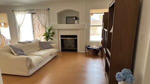 Ein Wohnzimmer mit einer Couch, einem Kamin, Holzboden und einer großen Holztür.