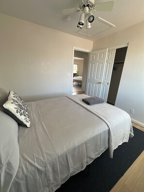 A bedroom with a bed, a ceiling fan, a door leading to another room, and a carpeted floor. - Clean and Cozy 3-bedroom house in peaceful Henderson with AC (henderson)