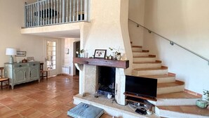 Un vaste espace de vie doté d’une cheminée, d’un escalier et d’un balcon.