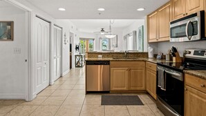 A modern kitchen with wooden cabinets, stainless steel appliances, and a granite countertop.