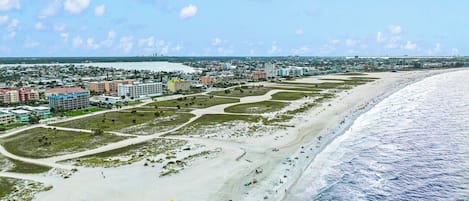 A coastal cityscape with a wide beach, buildings, and a clear sky.
