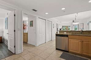 A modern kitchen with a dishwasher, granite countertop, and wooden cabinets. - Sunset Views & Endless Balcony, On Site Heated Pool and Spa, Steps to Beach (Treasure Island)