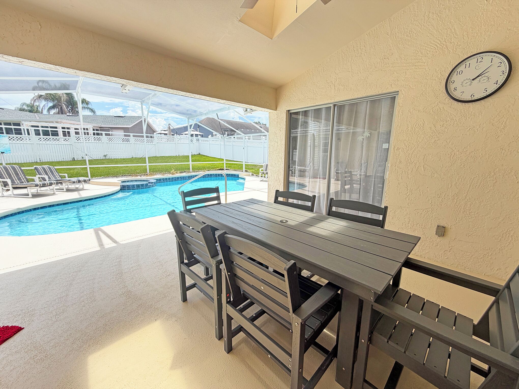 Ein Balkon mit Pool, einem Tisch, Stühlen und einer Wanduhr.
