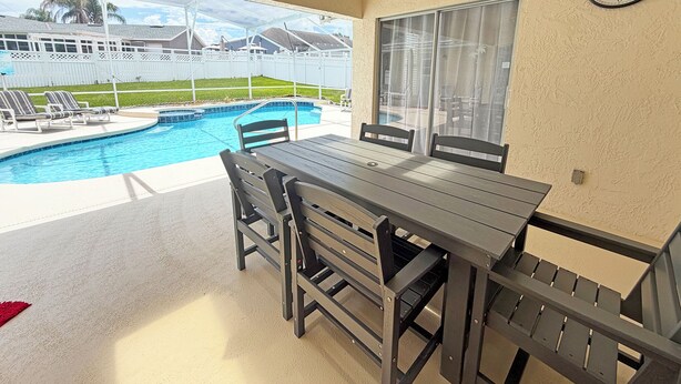 Ein Balkon mit Pool, einem Tisch, Stühlen und einer Wanduhr.