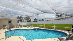 Ein Schwimmbad mit überdachtem Bereich, Liegestühlen und einem umzäunten Garten.