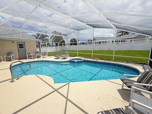 Una piscina con zona cubierta, sillas de descanso y un patio cercado.