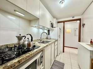 A modern kitchen with a gas stove, kettle, microwave, and a built-in oven.