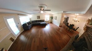 A spacious living room with hardwood flooring, a sectional sofa, a ceiling fan, and a dining area with chairs and a table. - Executive 5BR Retreat Ft. Jackson Hospitals USC (West Columbia)
