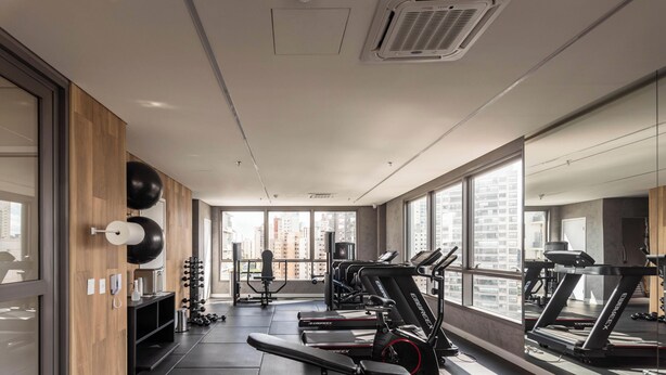 Ein Fitnessstudio mit Laufbändern, Gewichten und einem großen Fenster mit Blick auf die Stadt.
