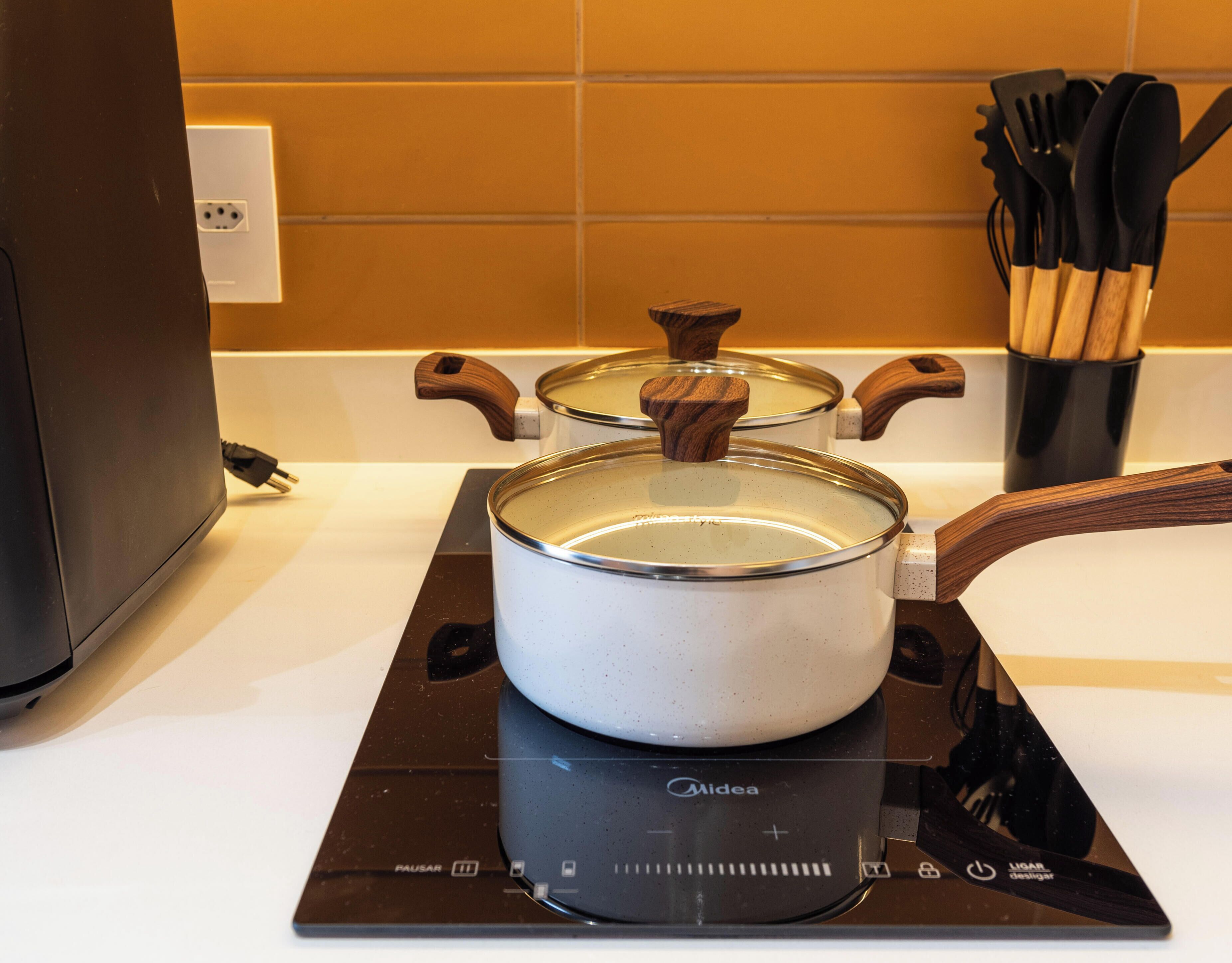 A kitchen with a stove, a pot on it, and a set of wooden utensils in a holder.