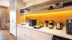 Eine moderne Küche mit integriertem Mikrowellenherd, Kaffeemaschine und Wasserkocher.