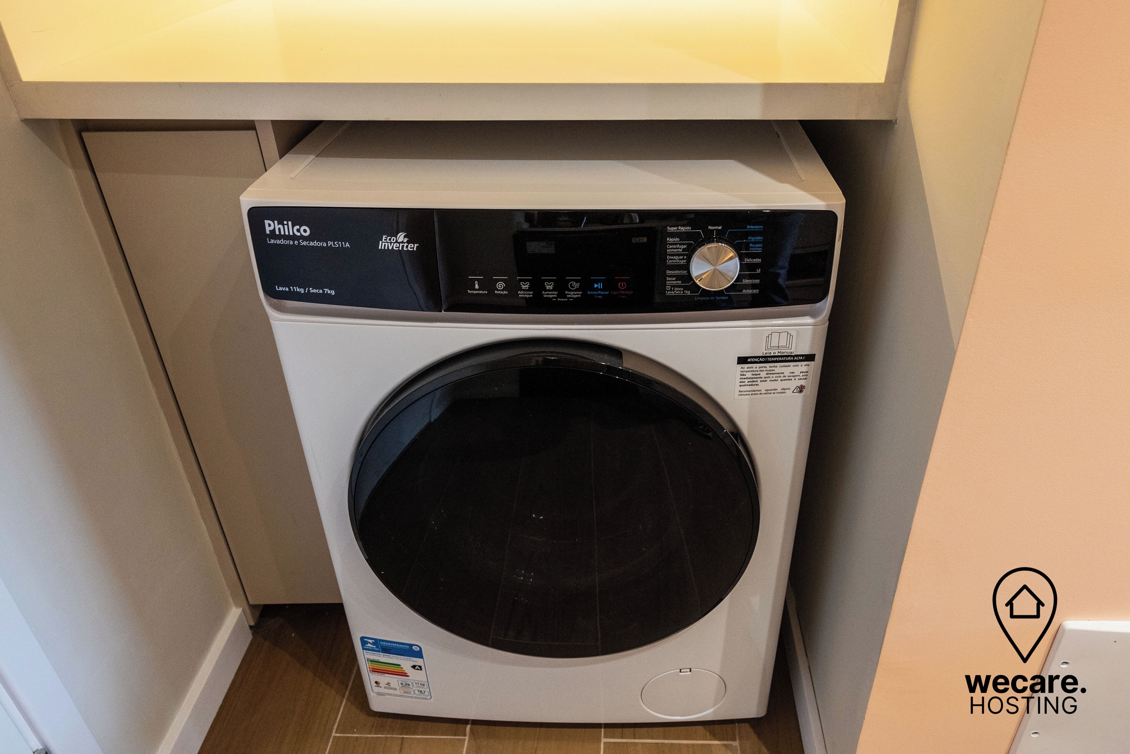 En kompakt tvättmaskin med frontmatning och en digital kontrollpanel, placerad under ett köksskåp.