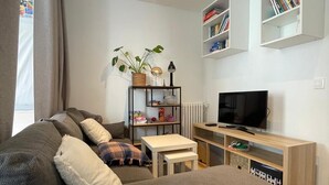 Ett modernt vardagsrum med en grå soffa, ett litet vitt bord, en tv och inbyggda bokhyllor.