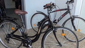 Dos bicicletas estacionadas adentro, una con asiento marrón y la otra con asiento negro.