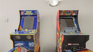 Two arcade machines against a plain wall, one with a space theme and the other with a Marvel theme. - New 2BR Skywalk Apt+Downtown Indy+Sleeps 7 (Indianapolis)