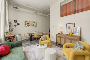 Un salon moderne comprenant un canapé, des fauteuils, une table basse et un coin repas avec une table et des chaises.