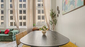 A room with a round table, a sofa, and a window with curtains. - New 2BR Skywalk Apt+Downtown Indy+Sleeps 7 (Indianapolis)
