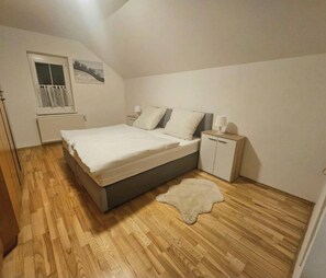 A bedroom with a bed, bedside tables, a window, and a radiator.