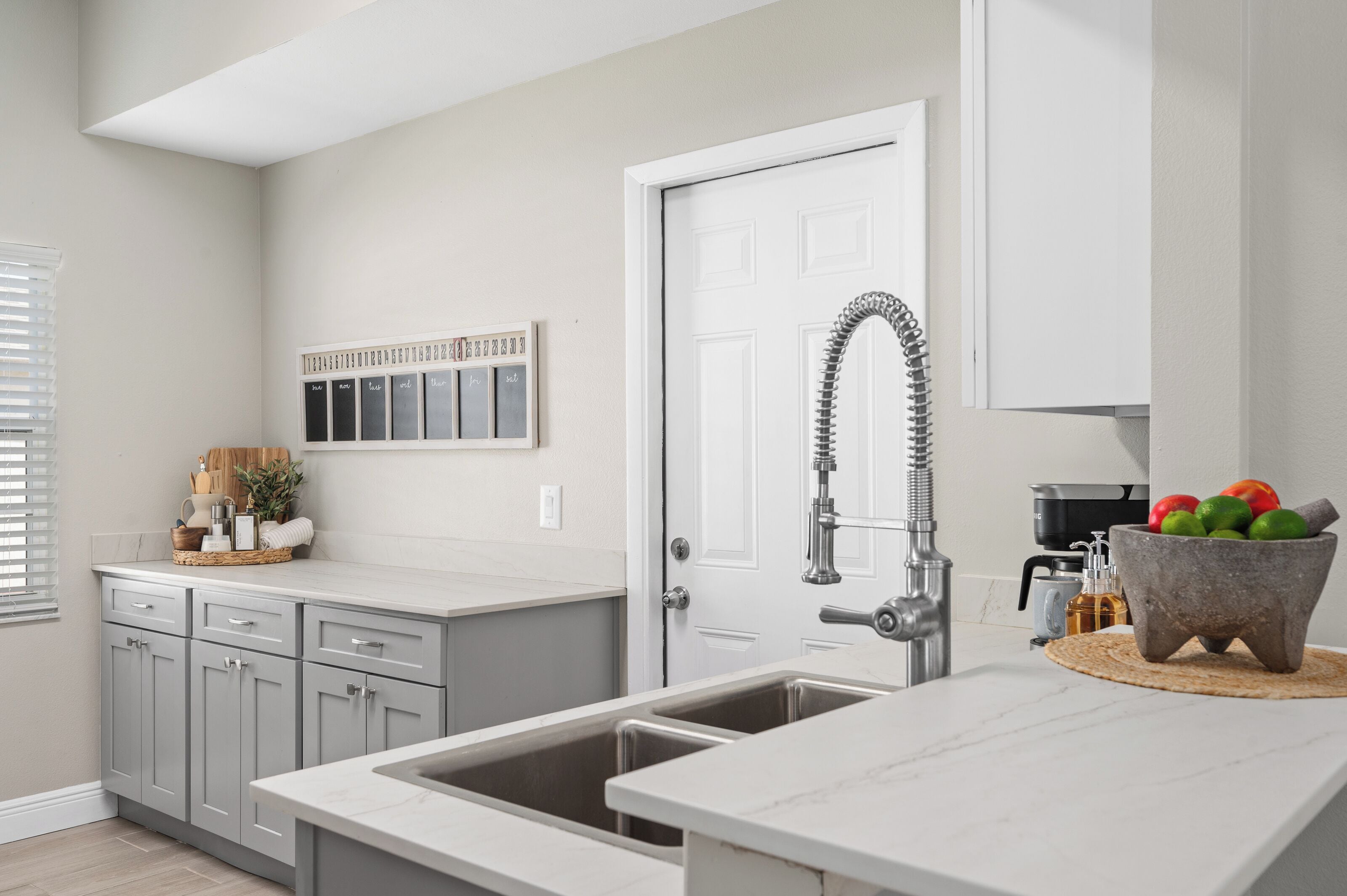 A kitchen with a double sink, a white door, and a wall-mounted spice rack.