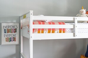 Ein Stockbett mit einer bunten Decke und einem Plüschtier darauf.