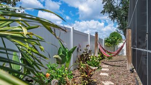 A garden with a hammock, plants, and a white fence. - 3BR Home with Private Pool Minutes from Disney (Kissimmee)