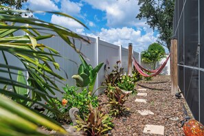A garden with a hammock, plants, and a white fence. - 3BR Home with Private Pool Minutes from Disney (Kissimmee)