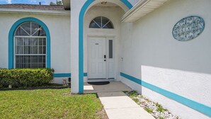 A house with a white exterior, blue trim, a front door, and a mailbox. - 3BR Home with Private Pool Minutes from Disney (Kissimmee)